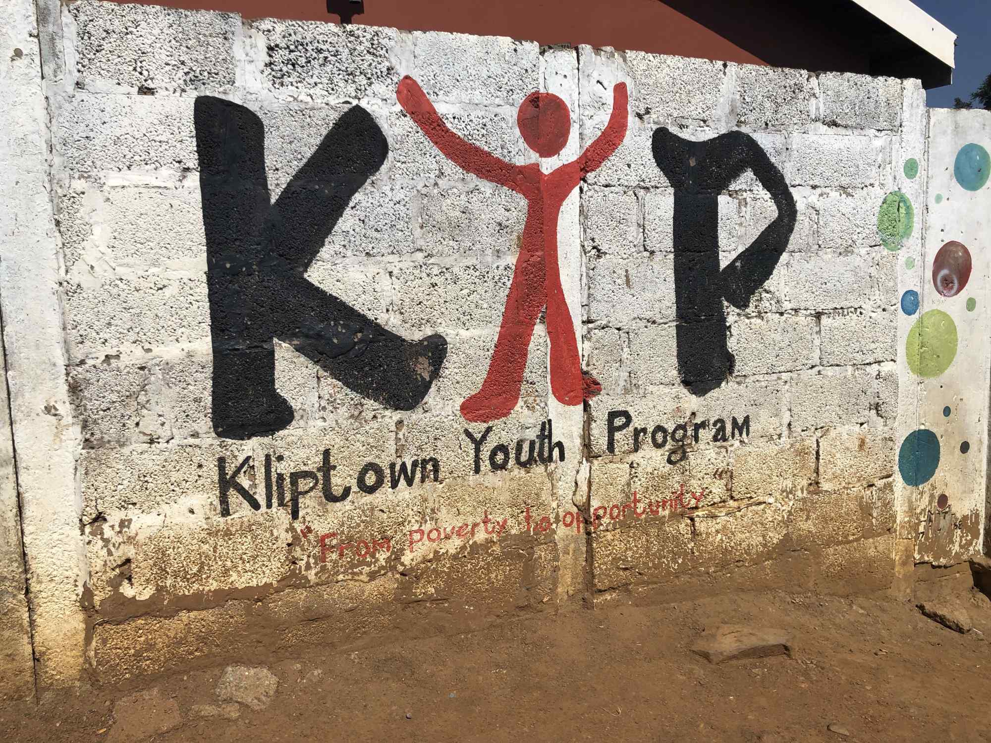 A vibrant street mural on a concrete block wall featuring the letters 'KYP' in bold black and red