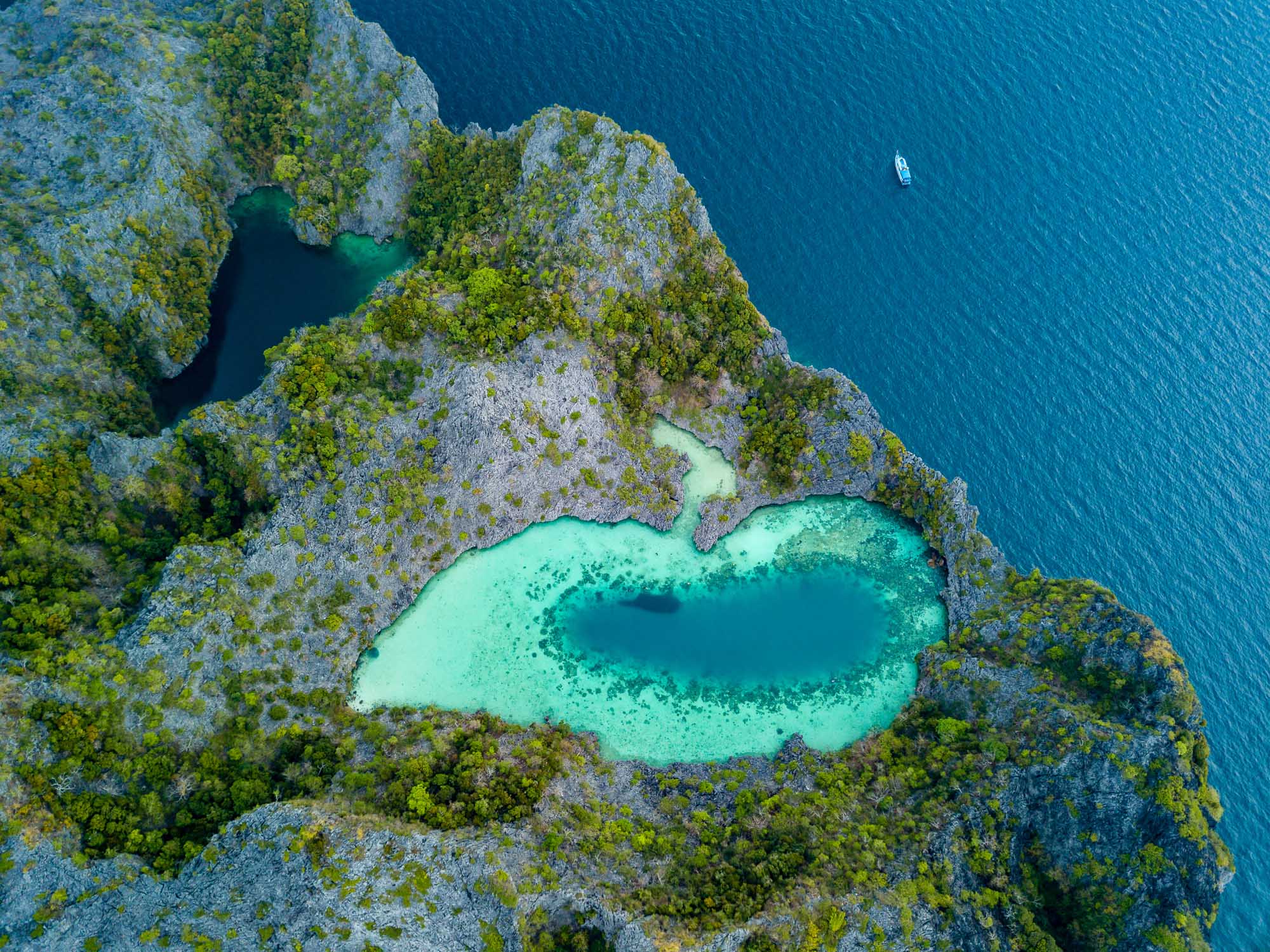 An aerial drone view of the iconic Shark Lagoon nestled within limestone karst formations on Cock