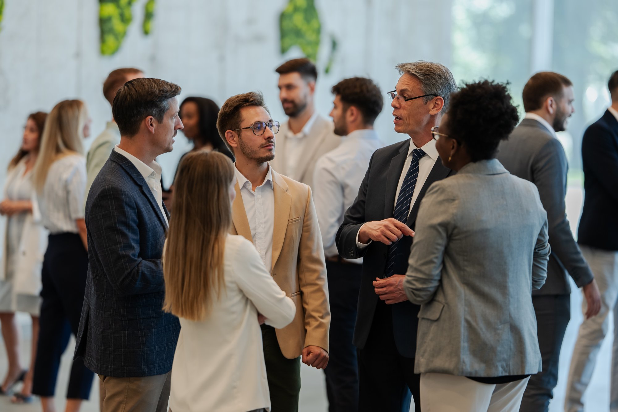 A diverse group of business professionals engaged in conversation and networking at what appears