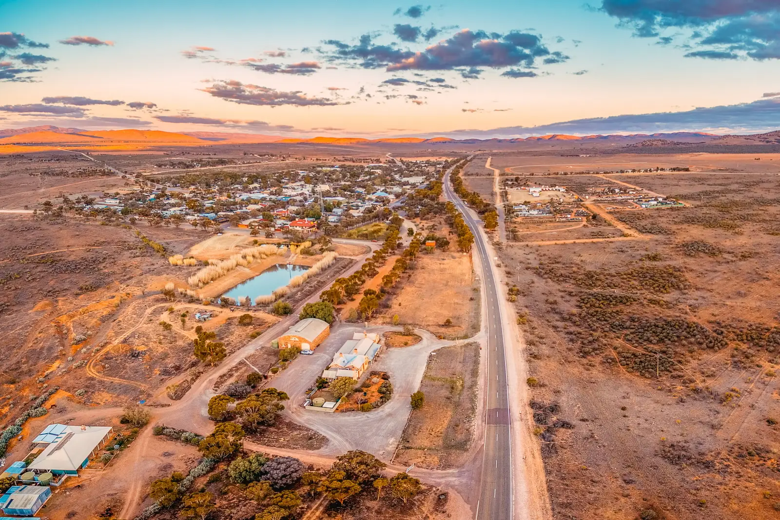 An expansive aerial photograph of a sprawling rural town nestled in an arid valley, with