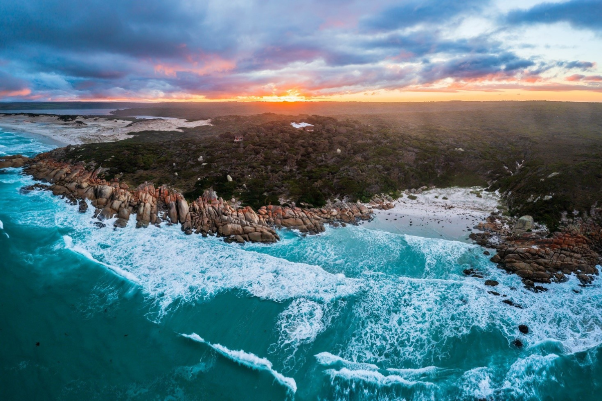 A dramatic aerial view of the Bay of Fires in Tasmania, featuring turquoise waters
