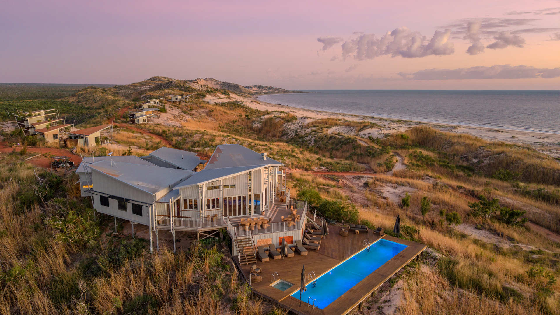 A modern elevated beachfront lodge featuring a distinctive curved white architecture with dual