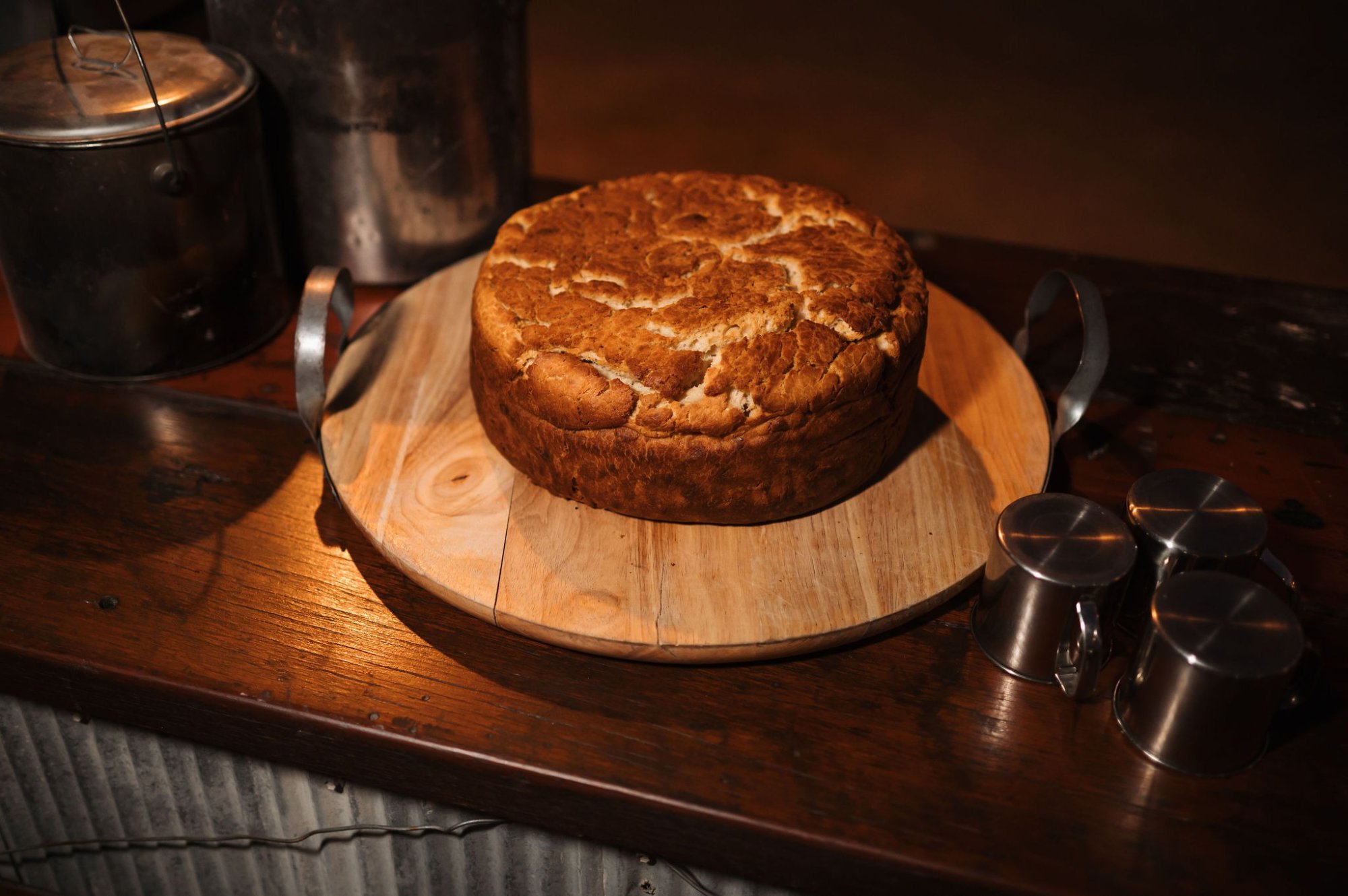 A rustic, crusty artisan bread loaf with a golden-brown exterior and deep scoring marks sits on