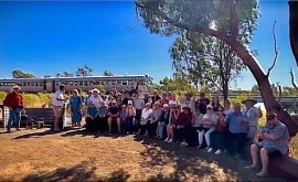 Group Gathering at Outback Outdoor Event A large group of people gathered outdoors in an arid, sandy landscape under clear blue skies