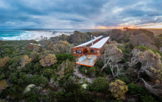 A striking modern red and white architectural structure perched on a forested clifftop overlooking