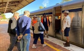 Passengers Boarding Commuter Train at Station A group of passengers boarding and exiting a modern commuter train at a transit station platform