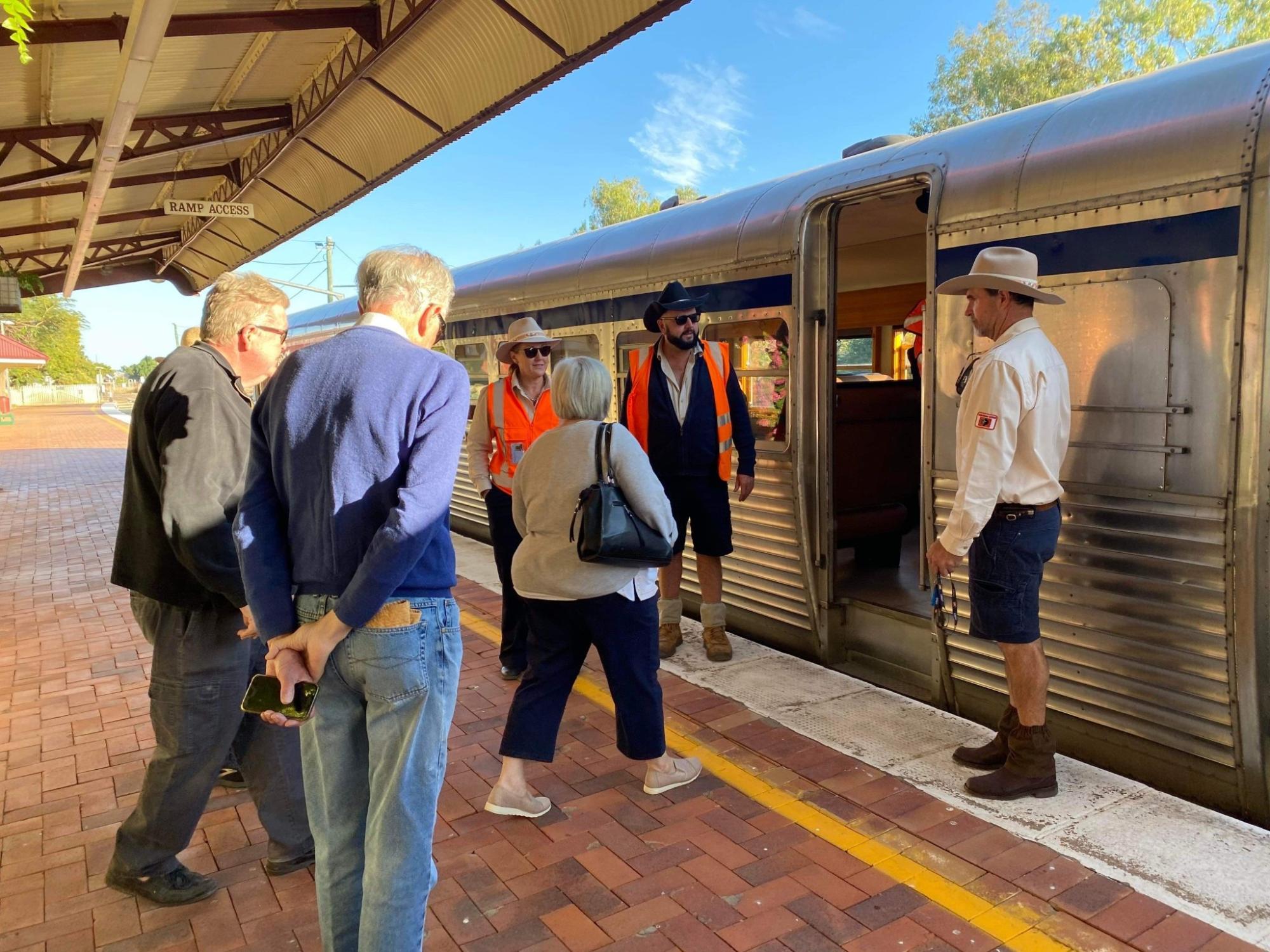 Passengers Boarding Regional Train at Station A group of passengers and staff gathered at a regional train platform during boarding. The scene