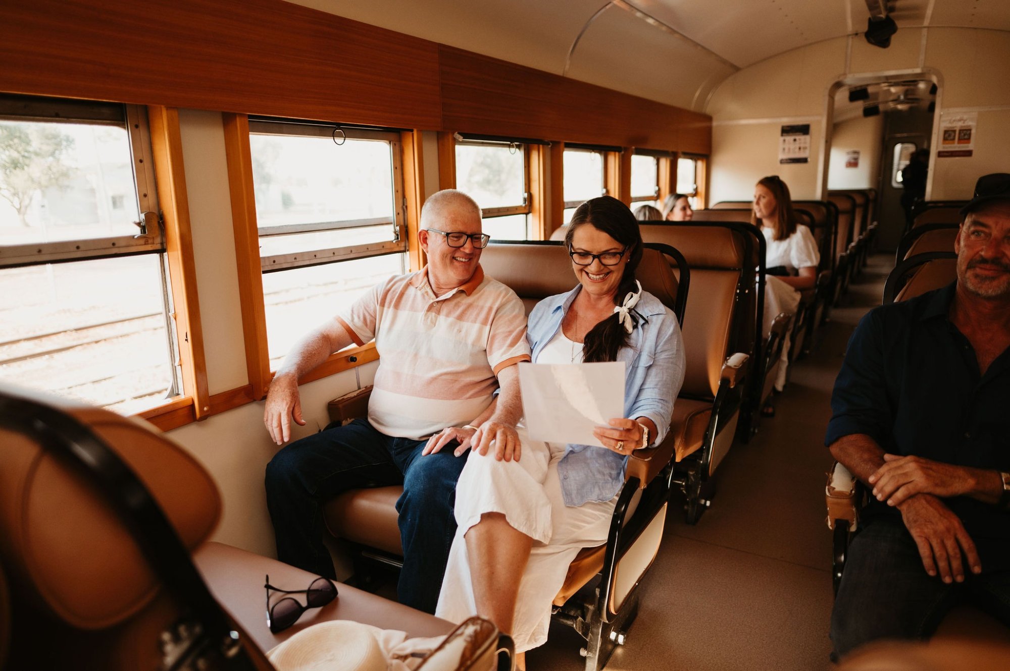 A group of happy travelers enjoying a scenic bus ride, with a couple in the foreground smiling