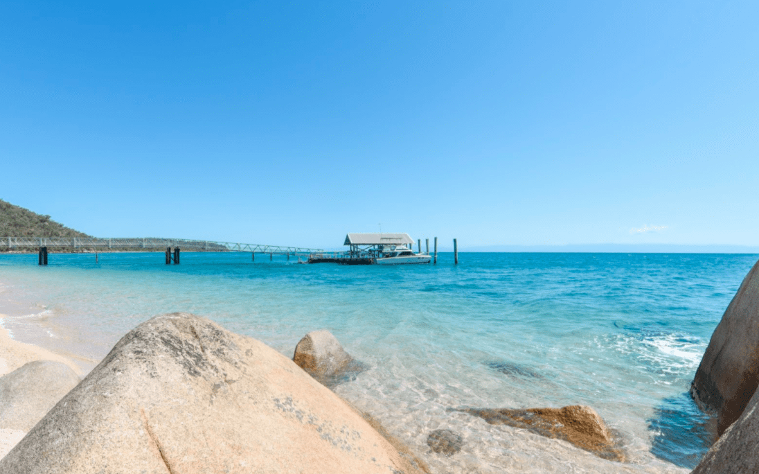 A stunning tropical beach scene featuring crystal-clear turquoise waters, white sand, and granite