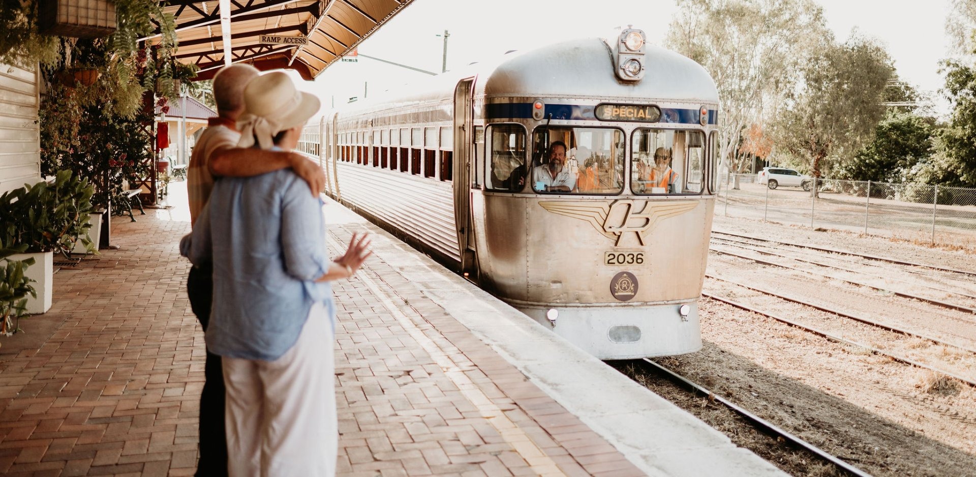 A vintage streamliner train numbered 2036 pulls away from a mid-century railway station platform