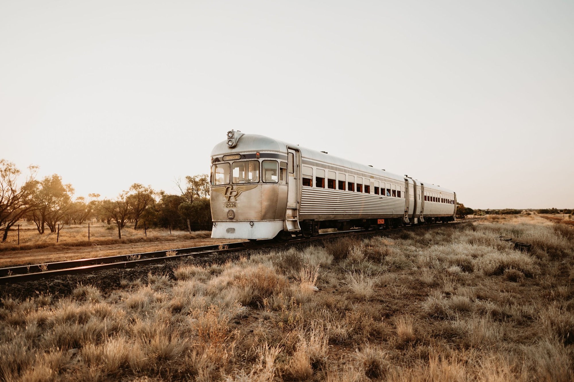A silver Art Deco streamliner passenger train numbered 2035 travels through an arid desert
