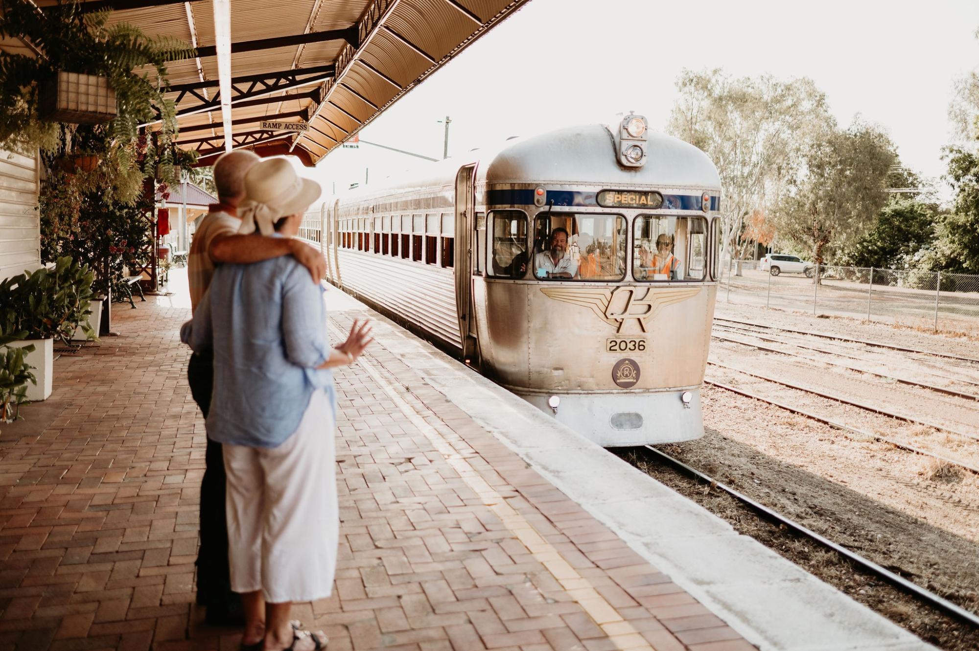A woman in light blue clothing and a hat boards a classic streamliner passenger train numbered 2036
