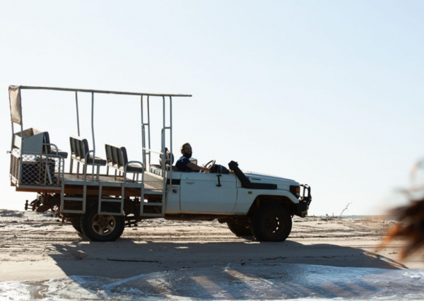 An open 4WD safari vehicle on the sand during a Kimberley coastal beach drive from Berkeley River Lodge