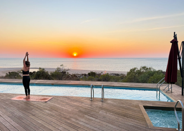 A guest practising yoga on the pool deck at Berkeley River Lodge as the sun rises over the Timor Sea