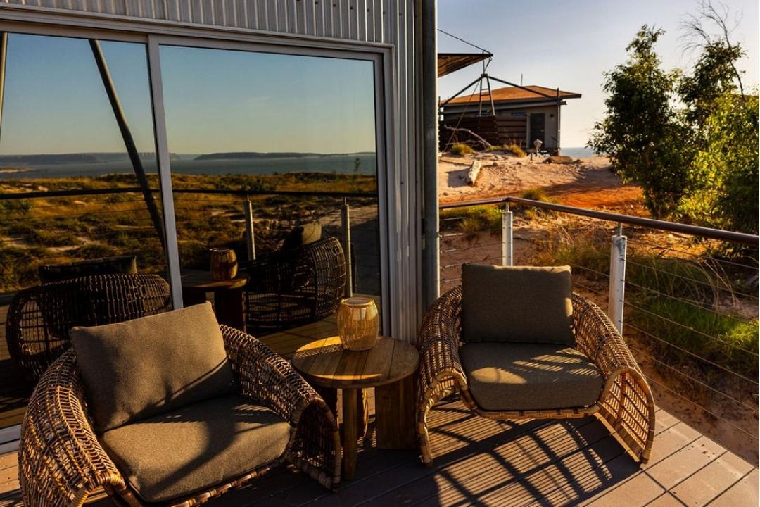 A serene hilltop villa balcony featuring woven outdoor furniture with plush cushions overlooking